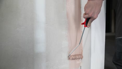 Close-up-of-man´s-hand-painting-a-wall-in-pink-color-with-paint-roller