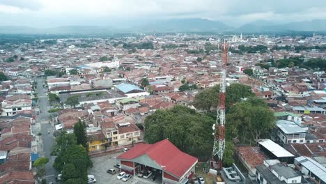 Vista-Aérea-De-Un-Pueblo-Rural-En-Colombia,-Con-Nubes-Flotando-Sobre-Las-Montañas-Al-Fondo