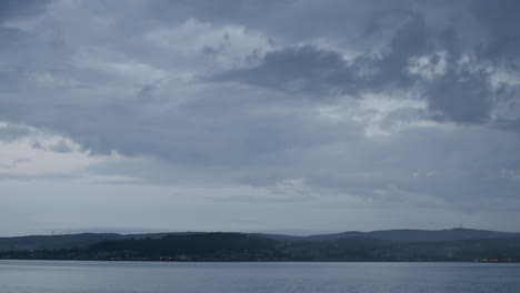 Timelapse-of-sea-and-sky-and-distant-town,-the-rain-comes-in