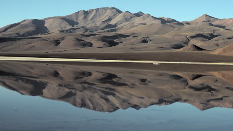 Pan-across-surreal-altiplano-landscape-hills,-salt-lagoon-reflection