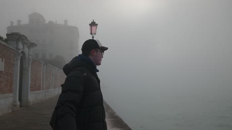 Tourist-Man-in-foggy-morning-by-Venice's-lamp-lit-path