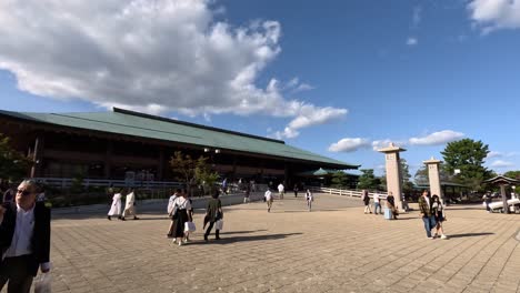 Visitors-stroll-along-the-square-area-in-front-of-the-Miyajima-Ferry-Terminal-building,-embodying-the-essence-of-travel-and-cultural-exploration