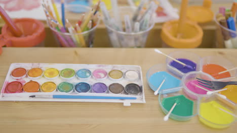 Watercolors-On-The-Table-With-Paint-Brush-And-Colored-Pencils