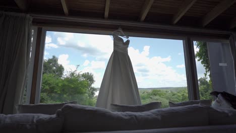 Wunderschönes-Langes-Weißes-Brautkleid-Hängt-Im-Offenen-Fenster-Des-Hotelzimmers-Mit-Blick-Auf-Die-Iguazú-Wasserfälle