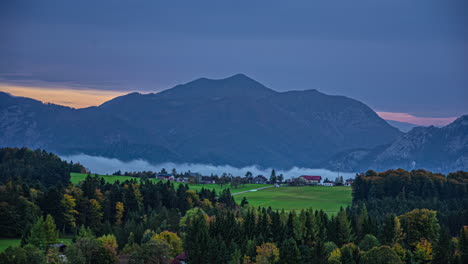 Time-lapse-pink-golden-skyline-clouds-moving-in-Austrian-alps-rural-valley-green-meadow-mountain-background