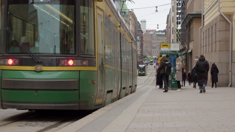 Electric-transit-train-comes-to-stop-on-cobbled-street-in-Helsinki-FIN