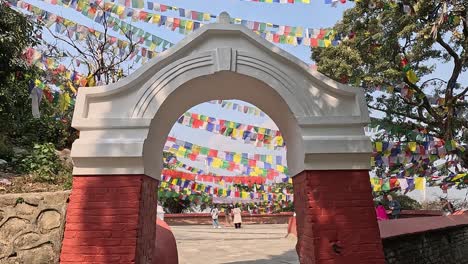 Opening-shot-moving-through-a-brick-arch-on-an-area-with-many-Tibetan-prayer-flags-in-the-sky