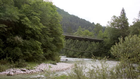 Historic-railway-bridge-over-a-crystal-clear-Alpine-river,-mountain-landscape