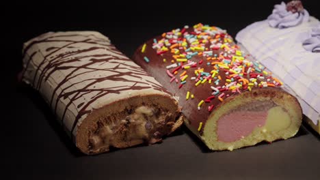 slider-panning-shot-of-Ice-cream-froster-swiss-cake-rolls-collection-with-black-background-oreo-blackberry-neapolitan-mix-with-sprinkles-and-mocca-mocha-flavors