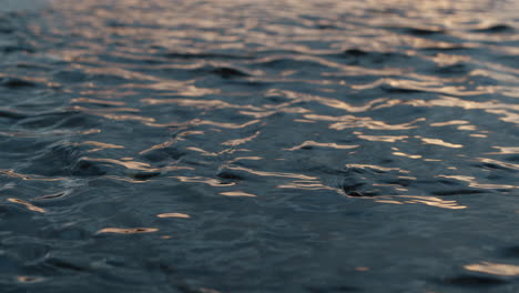 Shallow-water-flowing-in-ripples-at-sunset,-closeup