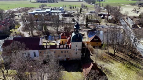 Panoramic-old-heritage-tower-house-in-north-eastern-Europe-village-Latvian-countryside-landscape,-aerial-drone-establishing-shot