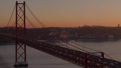 El-Resplandor-Anaranjado-Del-Atardecer-Se-Extiende-Entre-Los-Automóviles-Que-Viajan-Por-El-Puente-Colgante-En-Lisboa,-Portugal