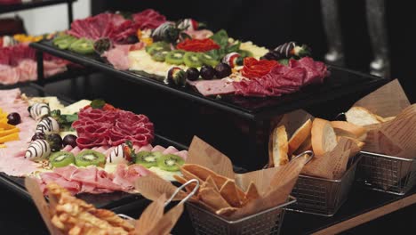 Charcuterie-board-with-different-fruits-and-baskets-of-breadsticks-arranged-at-banquet