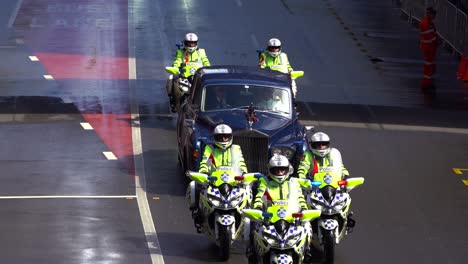 A-British-royal-car-is-escorted-by-police-officers-on-motorbikes-down-Adelaide-Street-as-part-of-the-annual-Anzac-Day-parade-tradition,-close-up-shot