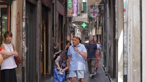 Slow-motion-clip-of-people-walking-along-narrow-street-in-Genoa,-Italy