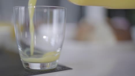 Orange-juice-is-poured-into-a-glass-in-slow-motion-as-the-camera-tracks-to-the-left