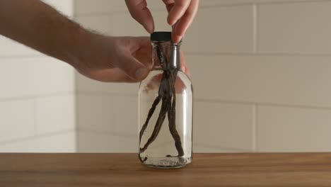 Male-hands-screwing-lid-on-top-of-vanilla-bottle-before-the-fermentation-process-has-taken-place