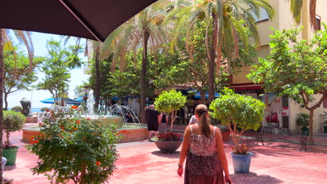 Hinter-Einem-Mädchen-In-Einem-Sommerkleid-In-Der-Altstadt-Von-Estepona-Spazieren,-Sonniger-Tag-In-Andalusien,-Spanien,-Urlaubsziel,-4k-Aufnahme