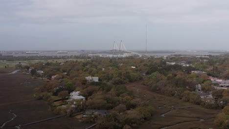 Aerial-wide-rising-shot-of-Ravenel-Bridge-from-Shem-Creek-on-a-hazy-day-in-Mount-Pleasant,-South-Carolina