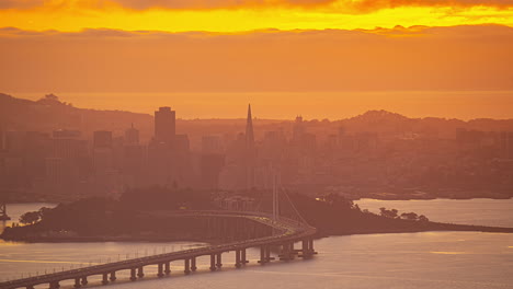 Time-lapse-of-the-Bay-bridge-and-the-San-Francisco-skyline,-hazy-sunset-in-USA