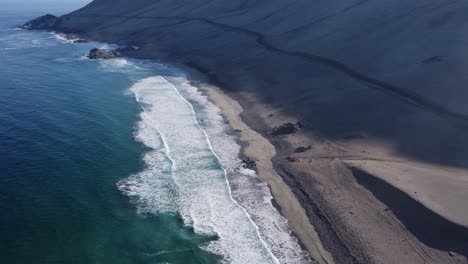 Single-road-cuts-across-sandy-mountain-slope-at-beach-in-coastal-Chile