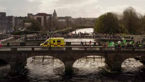 Retirada-Aérea-Sobre-El-Río-Corrib-Con-Un-Extraño-Puente-Salmón-A-La-Vista-Mientras-La-Gente-Observa-El-Desfile