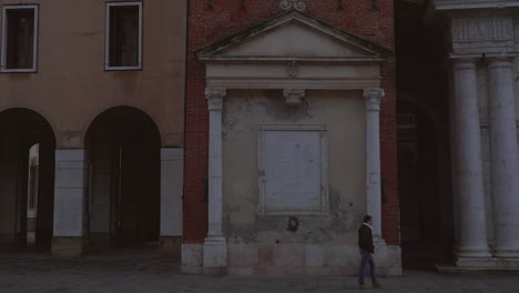 Pan-shot-view-of-a-person-walking-by-beautiful-and-old-Italian-building-in-Vicenza-Italy