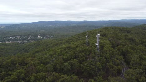 4K-aerial-drone-shot-of-a-Tv-broadcasting-Tower-on-the-mountain-with-winding-road-below