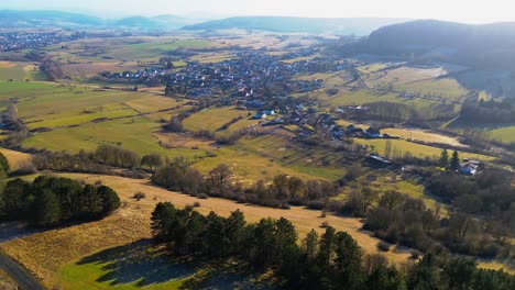 Ruhige-Luftaufnahme-Eines-üppigen-Ländlichen-Dorfes-Inmitten-Sanfter-Hügel