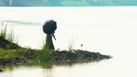 Fisherman-fishing-using-traditional-bamboo-wooden-rod-rural-village-Bangladesh
