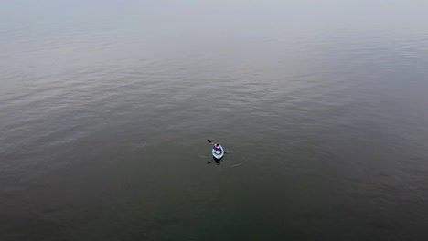 Aerial-Drone-shoots-Girl-on-a-kayak-paddling-on-a-cloudy-day