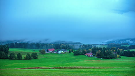 Small-village-in-Alps-with-thick-fog-flowing-above,-time-lapse-view