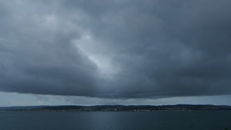 Heavy-dark-clouds-over-seaside-town-and-water