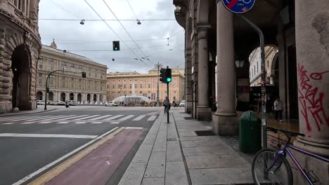 Handheld-clip-showing-city-road-and-junction,-with-people-walking-past-and-traditional-buildings-in-Italy