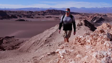 Lone-man-hikes-along-Atacama-desert-mountain-gravel-ridge-top-in-Chile