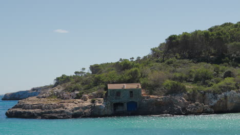 Secluded-coastal-house-on-rocky-shores-of-Cala-Mondrago,-Mallorca
