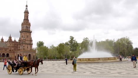 Turistas-Disfrutando-De-Un-Paseo-En-Carruaje-Tirado-Por-Caballos-En-La-Plaza-De-España,-Sevilla,-España---Toma-Estática