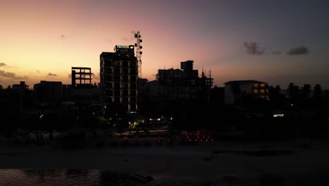 Sunset-silhouette-of-beachfront-Buildings-on-Maafushi-island,-Maldives,-Aerial