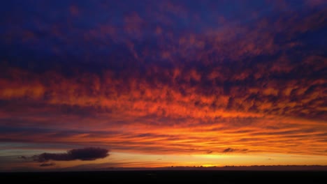 Altocumulus-Orange-Sonnenuntergang-Mit-Cumulus-Geformten-Wolken-Blauer-Himmel-Und-Schwarzem-Boden
