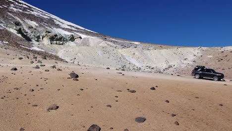 Mountain-aerial-pulls-out-to-reveal-truck-parked-on-summit-ridge