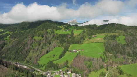 Die-Drohne-Fliegt-Schnell-Vorwärts-über-Chalets-Und-Alpenhäuser,-Die-Die-üppigen-Grünen-Grashügel-übersäen