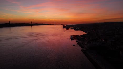 La-última-Luz-Del-Fuego,-El-Resplandor-Del-Atardecer,-Se-Extiende-Sobre-El-Río-Tajo-En-Lisboa,-Portugal,-Silueta-Del-Puente.