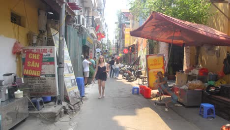 Through-narrow-city-alleyway-residents,-visitors-and-motorcycles-pass