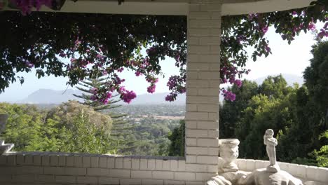 Viajando-Desde-Un-Balcón-De-Ladrillo-Blanco-A-La-Sombra-De-Buganvillas-Con-Vistas-Impresionantes