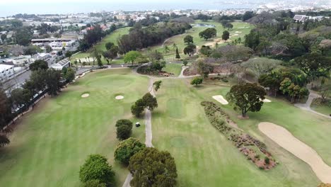 Aerial-view-golf-course-professional-players-practicing-the-sport,-background-city