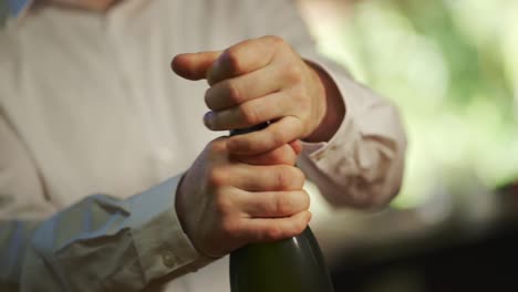 A-man-removes-the-cork-and-opens-a-bottle-of-champagne-to-celebrate