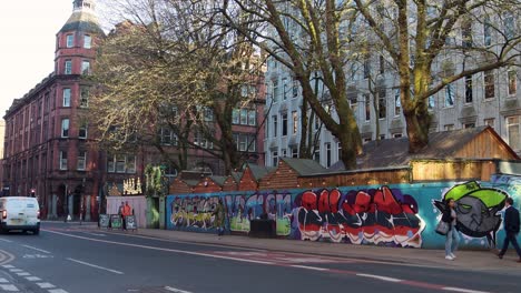 Urban-street-scene-with-vibrant-graffiti-in-Manchester's-Northern-Quarter,-passing-van-in-daylight