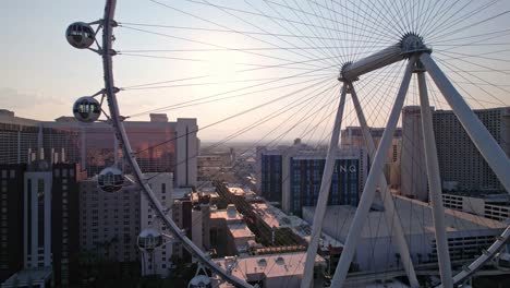 Aerial-drone-footage-of-the-sun-viewed-through-the-High-Roller-ferris-wheel-from-the-edge-of-the-wheel-tracked-through-the-middle-of-the-wheel-on-a-cloudless-evening-with-a-golden-glow