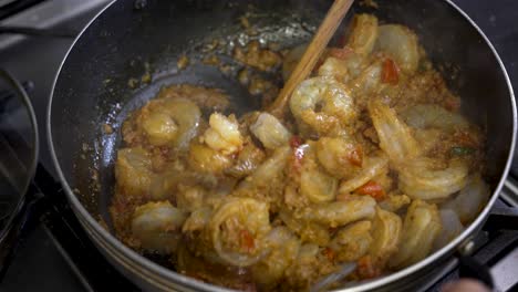 Curry-Garnelen-Gericht,-Das-Mit-Einer-Holzkelle-Umgerührt-Wird,-Während-Es-In-Der-Pfanne-Kocht