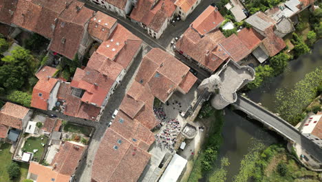Top-Down-Zoom-out-Aerial-View-of-Medieval-French-City-With-Open-Air-Theater-and-Green-River